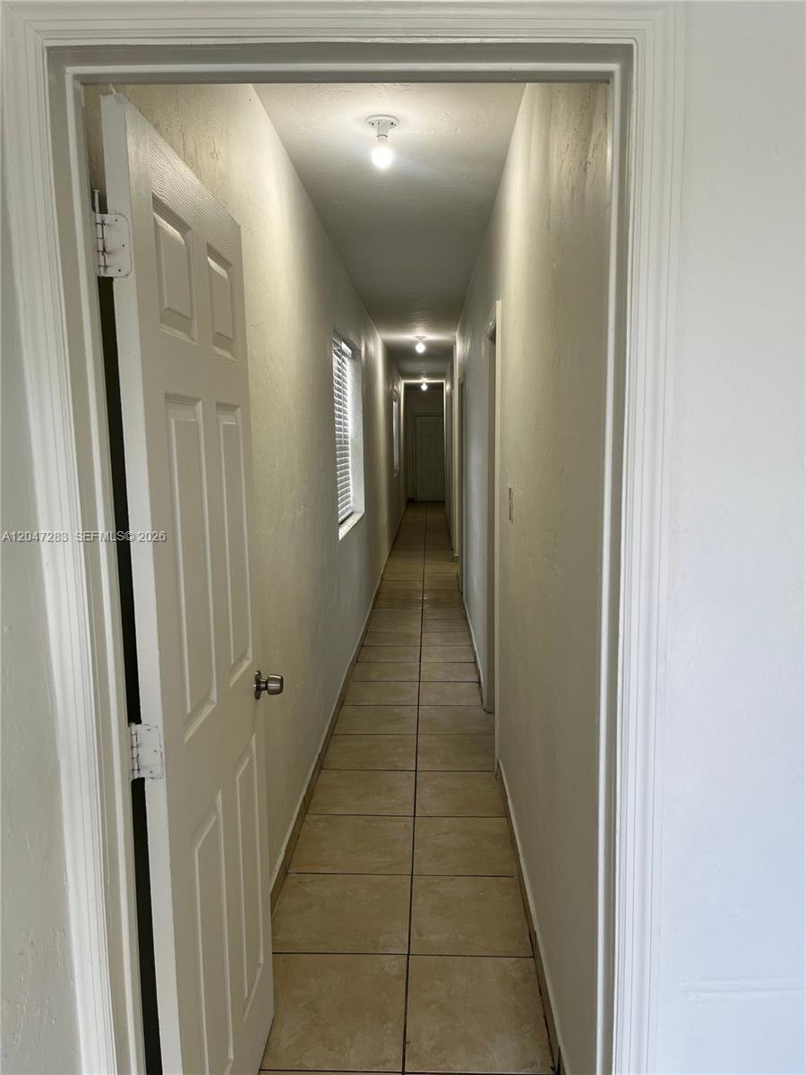 A long, narrow hallway features beige tile flooring, white walls, and multiple doorways — 733 NW 4th Ave, Miami FL 33136, MIAMI, FL
