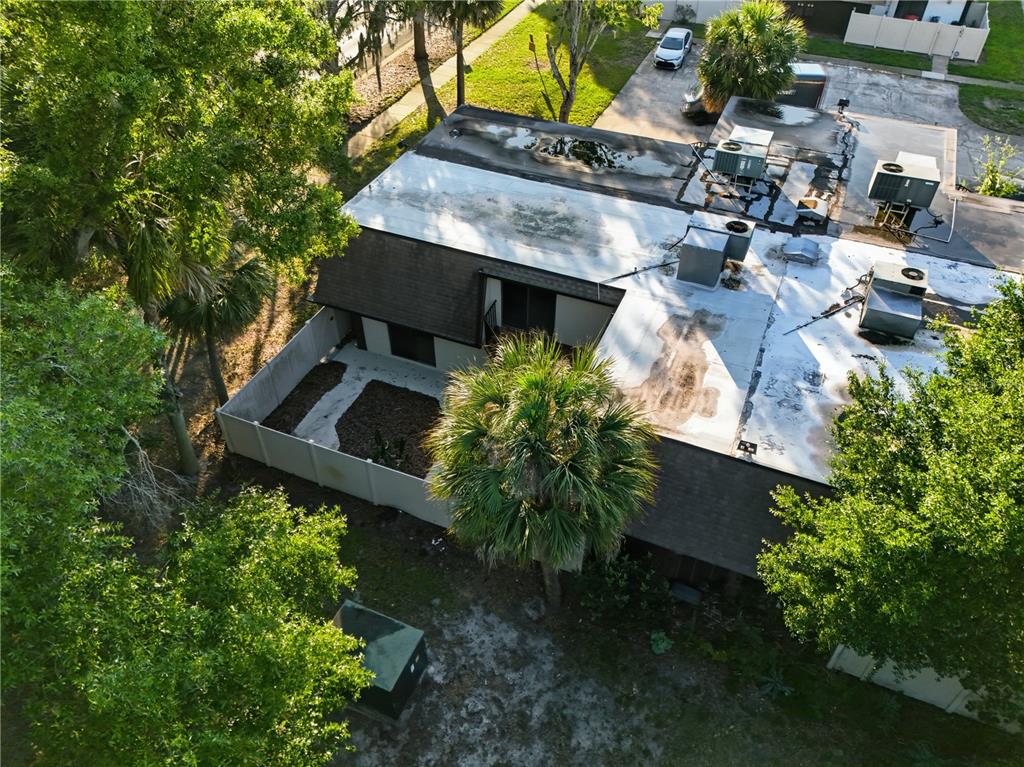 An aerial view shows a building with a flat roof, HVAC units, and a fenced courtyard — 4026 SHANNON BROWN DRIVE, ORLANDO, FL