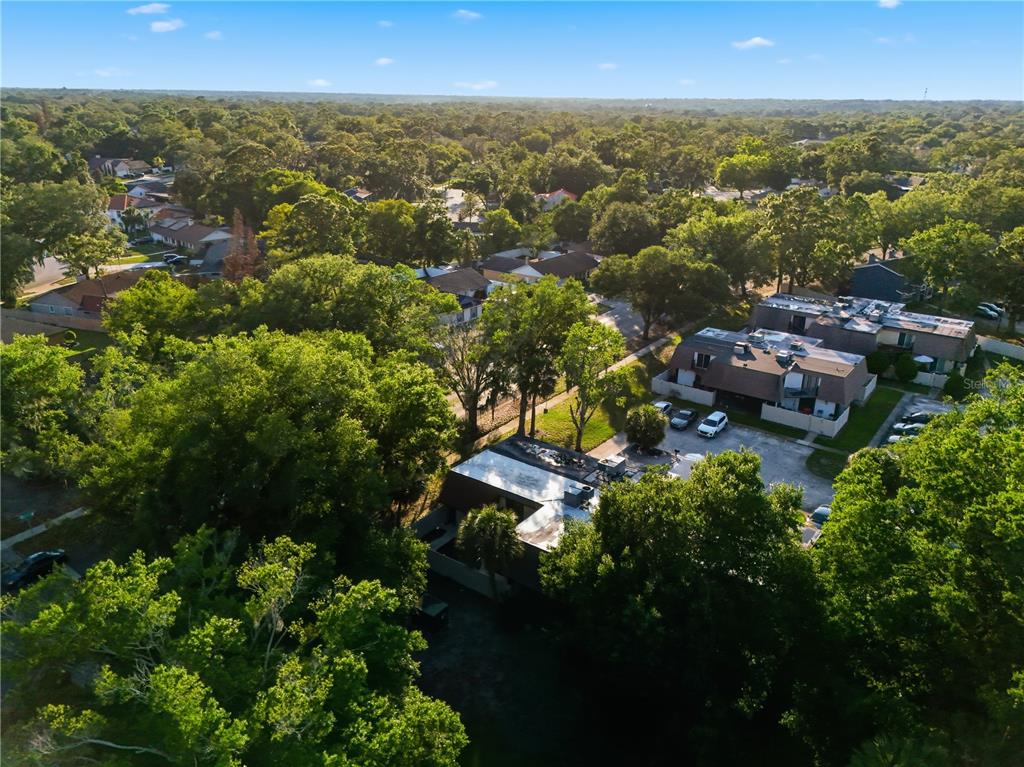 An aerial view shows a multi-unit residential building surrounded by dense trees and parking areas — 4026 SHANNON BROWN DRIVE, ORLANDO, FL