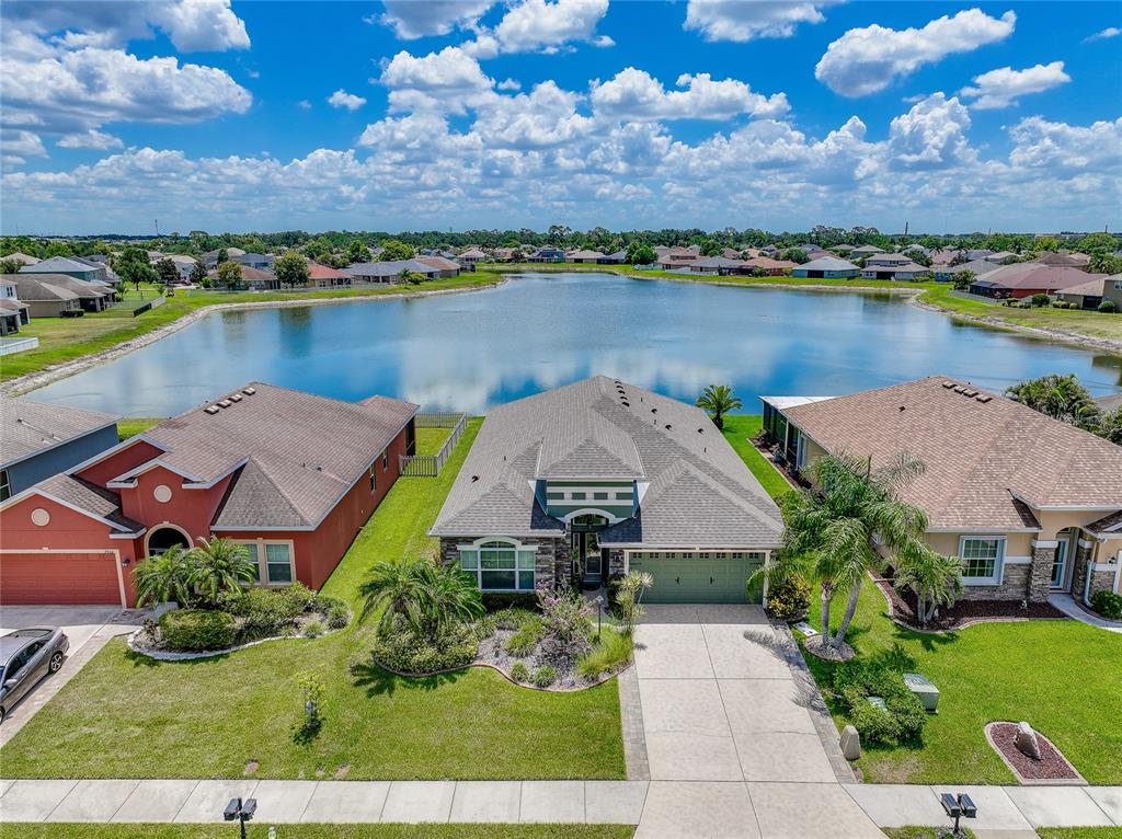 An aerial view shows a suburban house with a green garage facing a large lake — 7830 113TH AVENUE E, PARRISH, FL