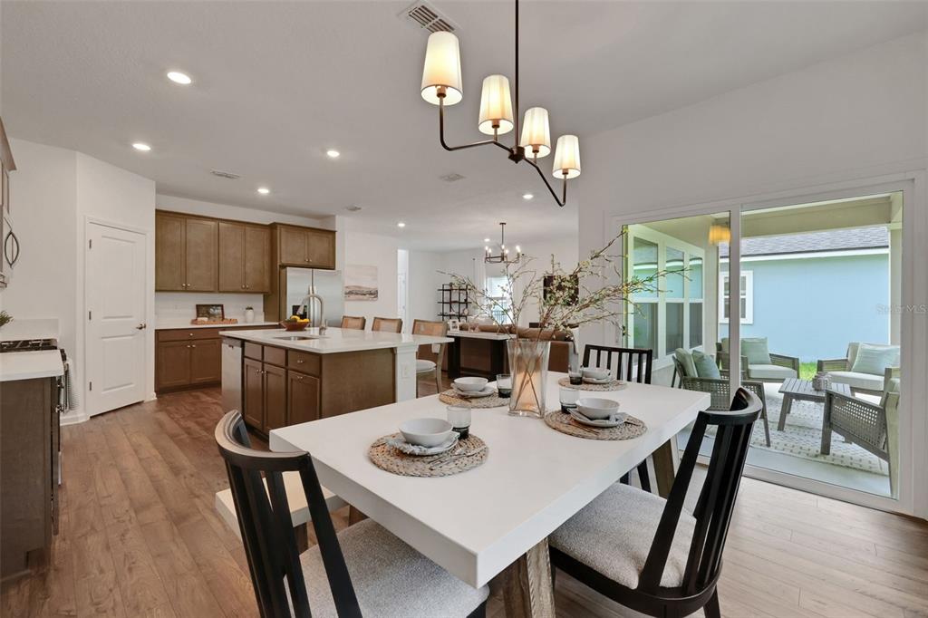 A dining area with a white table and black chairs opens to a kitchen and patio — 5716 LAGOON CRUISE WAY, JACKSONVILLE, FL