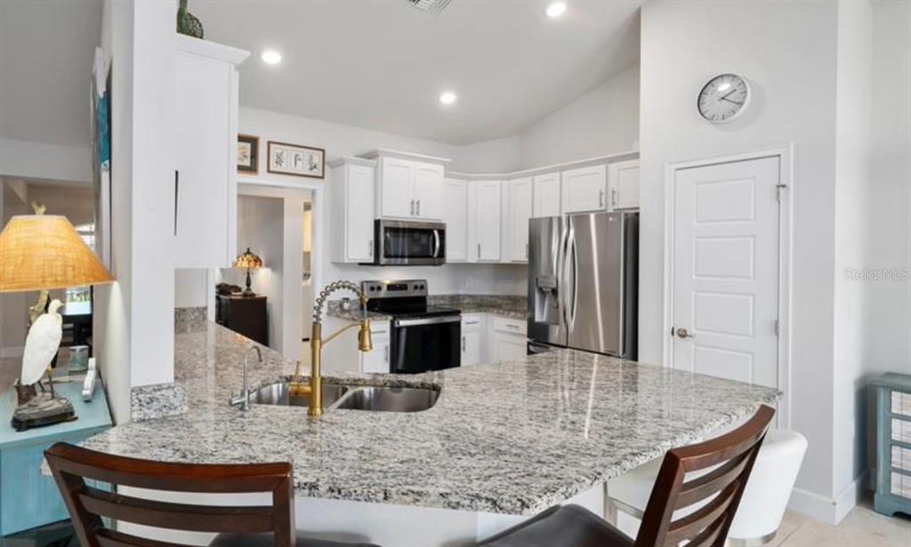 A kitchen with white cabinets, granite countertops, stainless steel appliances, and a breakfast bar — 8516 WATERSTONE BOULEVARD, FORT PIERCE, FL