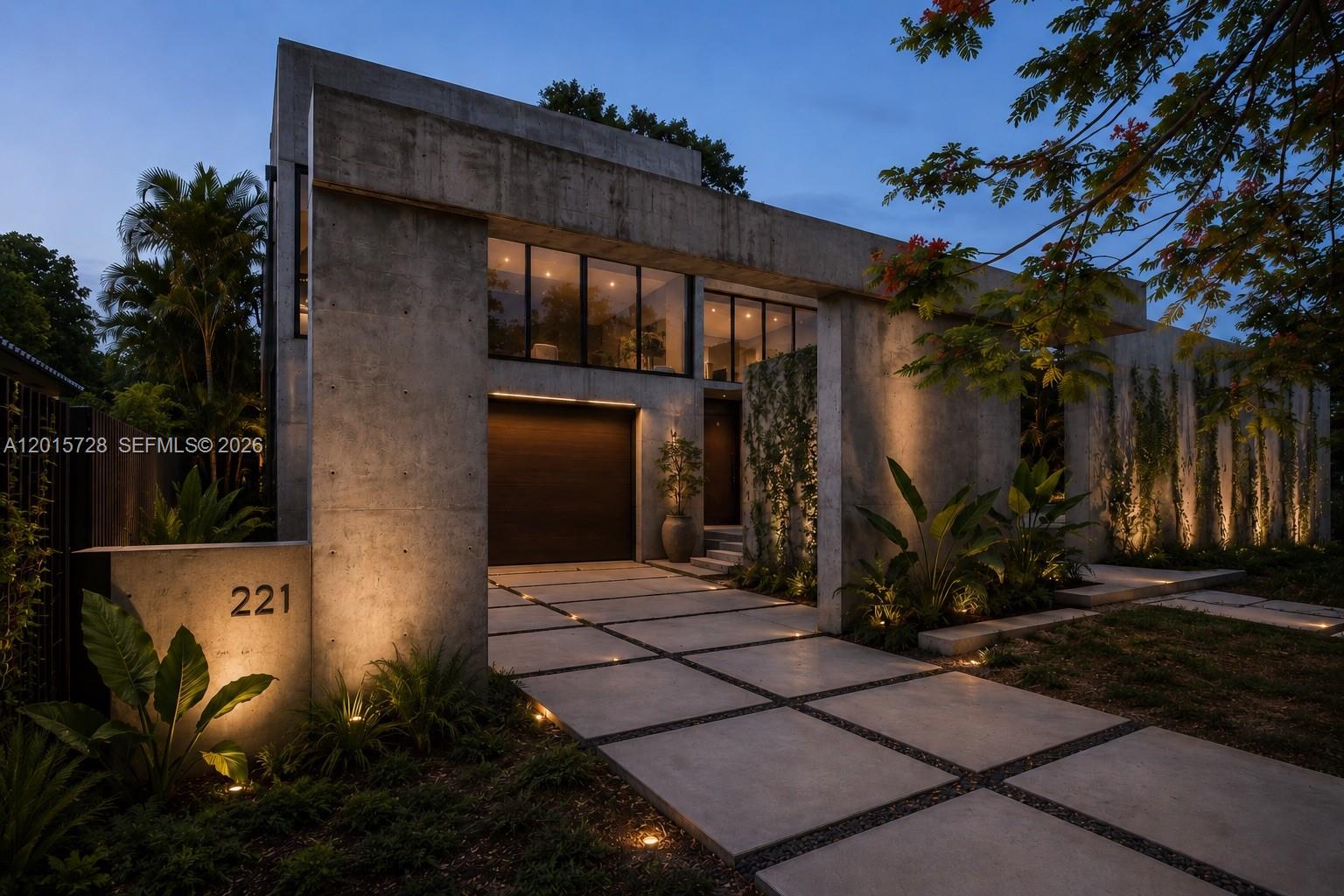 A modern concrete house exterior features a garage, large windows, and illuminated paved driveway — 221 SW 25th Rd, Miami FL 33129, MIAMI, FL