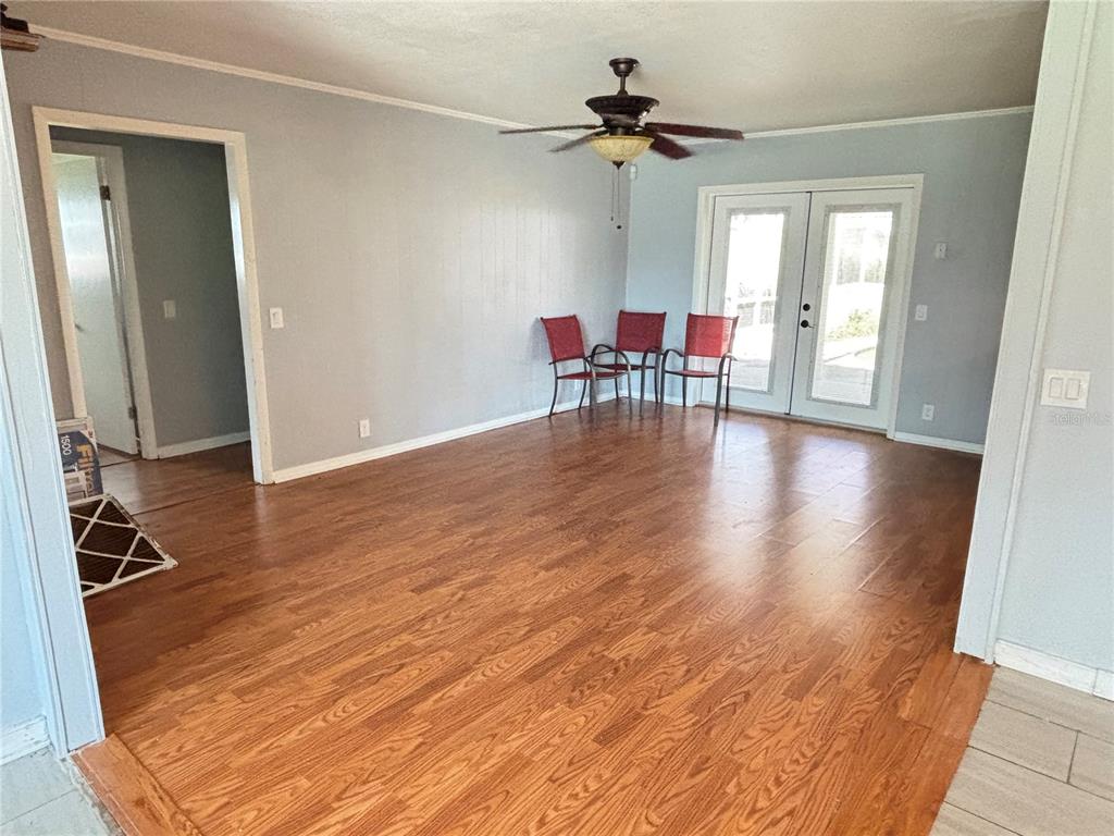 A living room with light gray walls, wood-look flooring, a ceiling fan, and French doors — 212 OVERLOOK DRIVE, WINTER HAVEN, FL