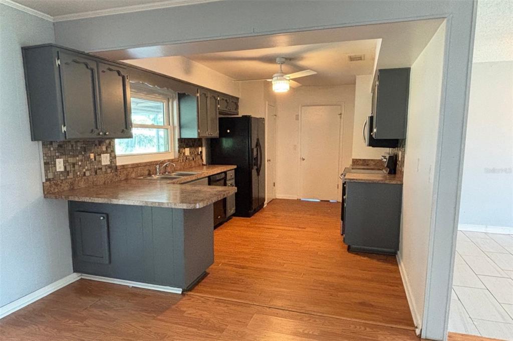 A kitchen features dark gray cabinets, a black refrigerator, and wood-look flooring — 212 OVERLOOK DRIVE, WINTER HAVEN, FL