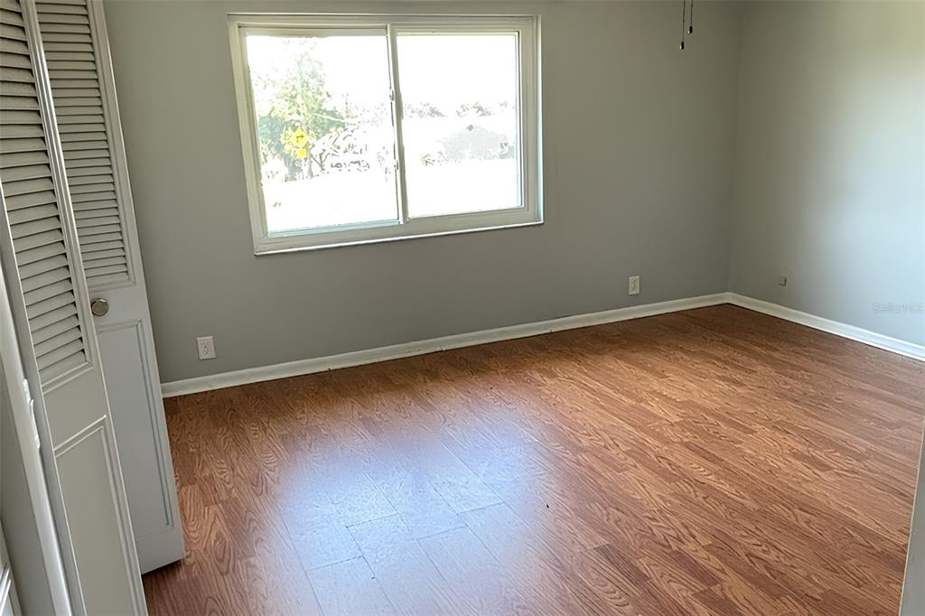 An empty bedroom features light gray walls, wood-look flooring, and a window overlooking a street — 212 OVERLOOK DRIVE, WINTER HAVEN, FL