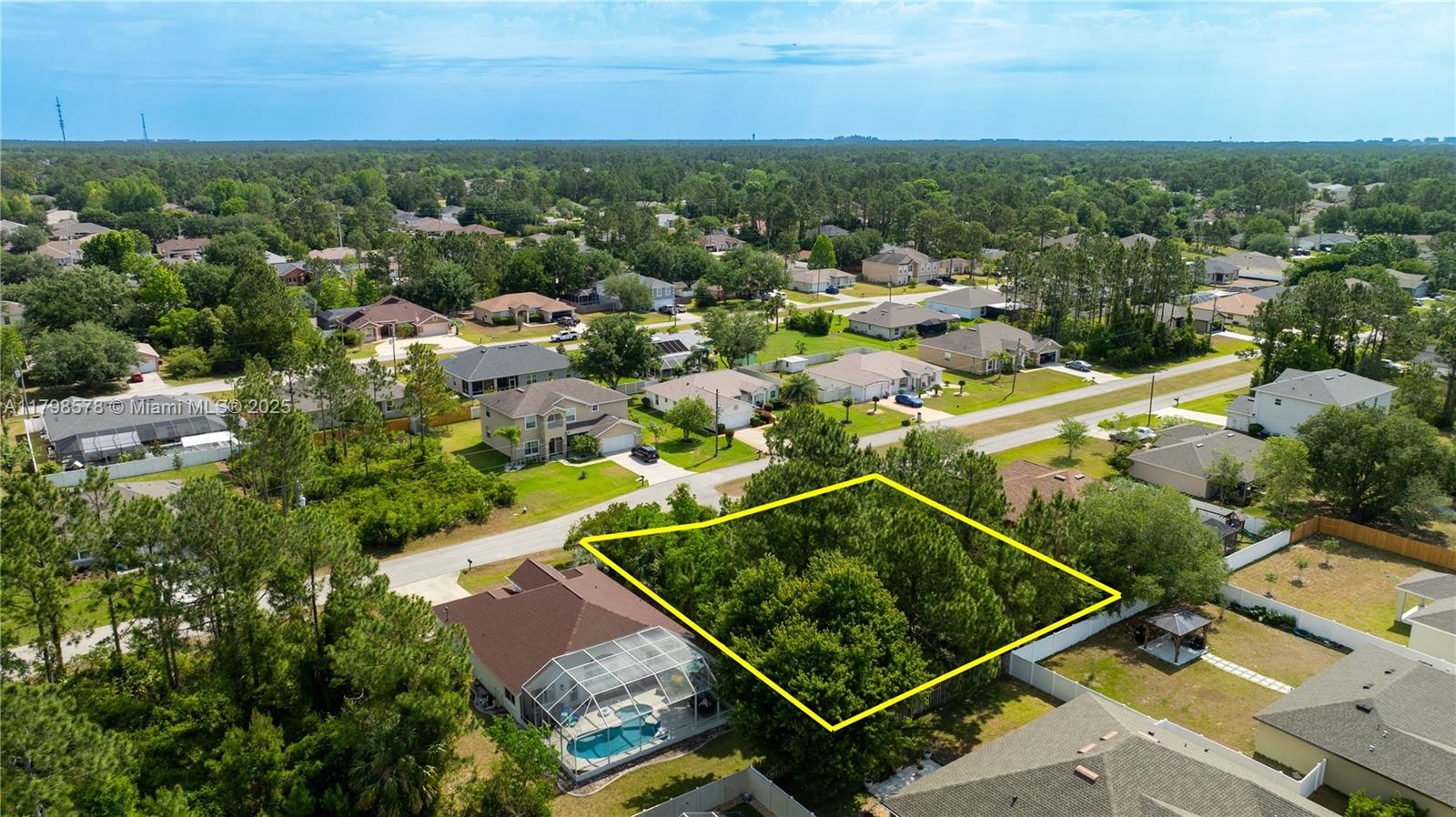 An aerial view shows a vacant, tree-covered residential lot outlined in yellow next to houses — 35 Butternut Dr., Palm Coast FL 32137, PALM COAST, FL