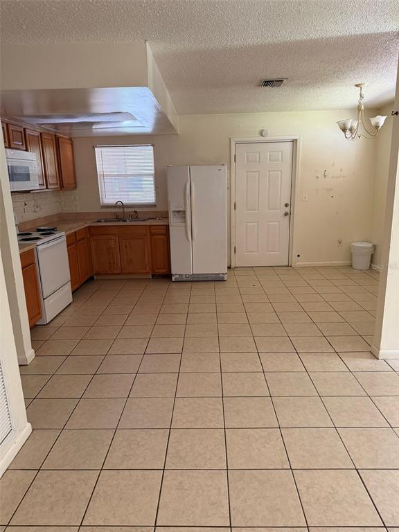 A kitchen with wood cabinets, white appliances, and beige tile flooring — 6458 79TH AVENUE N, PINELLAS PARK, FL