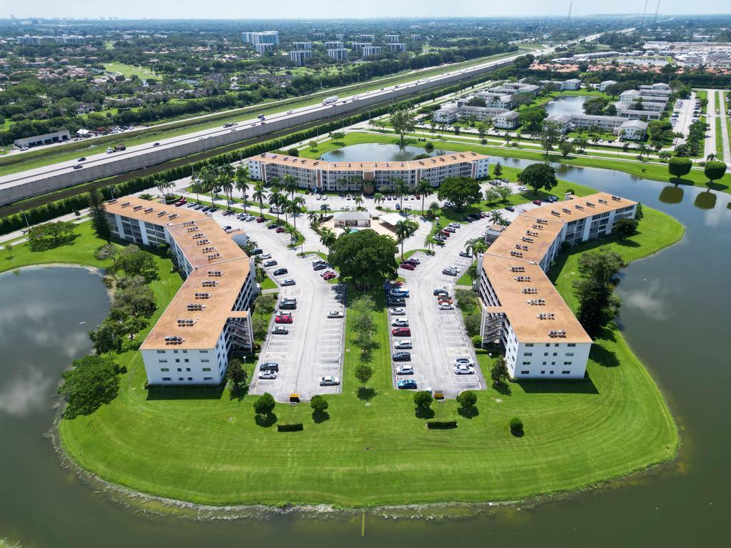 Aerial view of a multi-building apartment complex surrounded by water and a nearby highway — 2044 Hythe C, Boca Raton FL 33434, BOCA RATON, FL