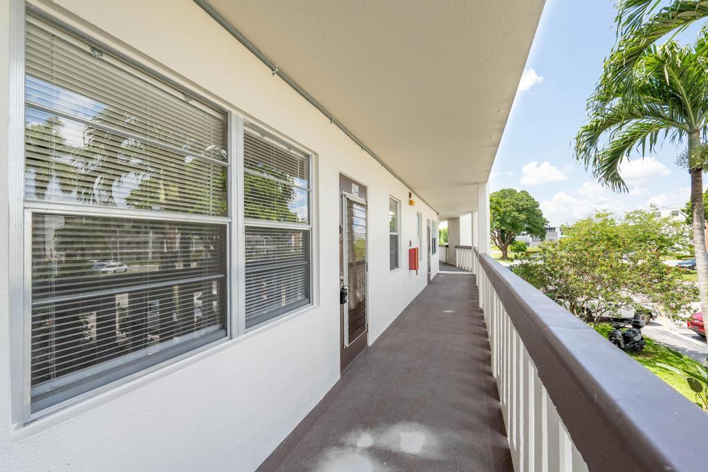 An exterior walkway with a concrete floor, white railings, and windows along a building wall — 2044 Hythe C, Boca Raton FL 33434, BOCA RATON, FL