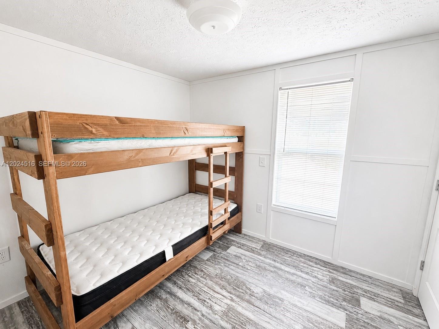 A bedroom features a wooden bunk bed, white walls, and light-colored wood-look flooring — 170 S Jinete St, Clewiston FL 33440, CLEWISTON, FL