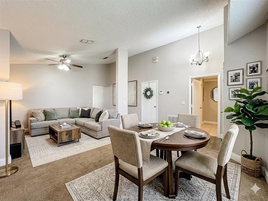 A living room with a sectional sofa and a dining area with a round table — 6582 MERITMOOR CIRCLE, ORLANDO, FL