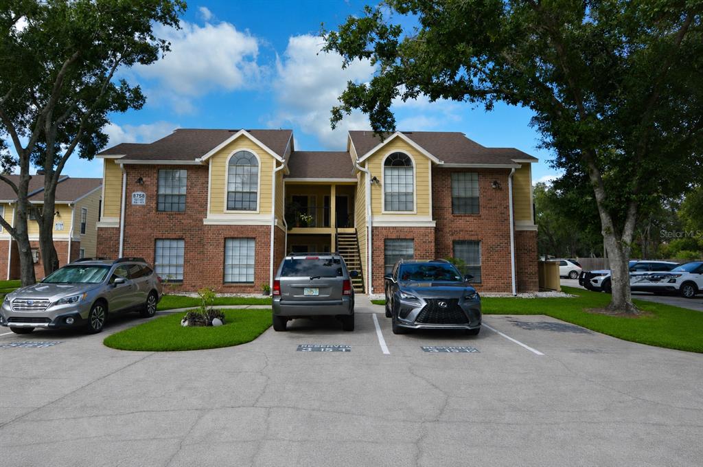 A two-story brick and yellow siding apartment building with three cars parked in front — 8758 MALLARD RESERVE DRIVE UNIT 101, TAMPA, FL