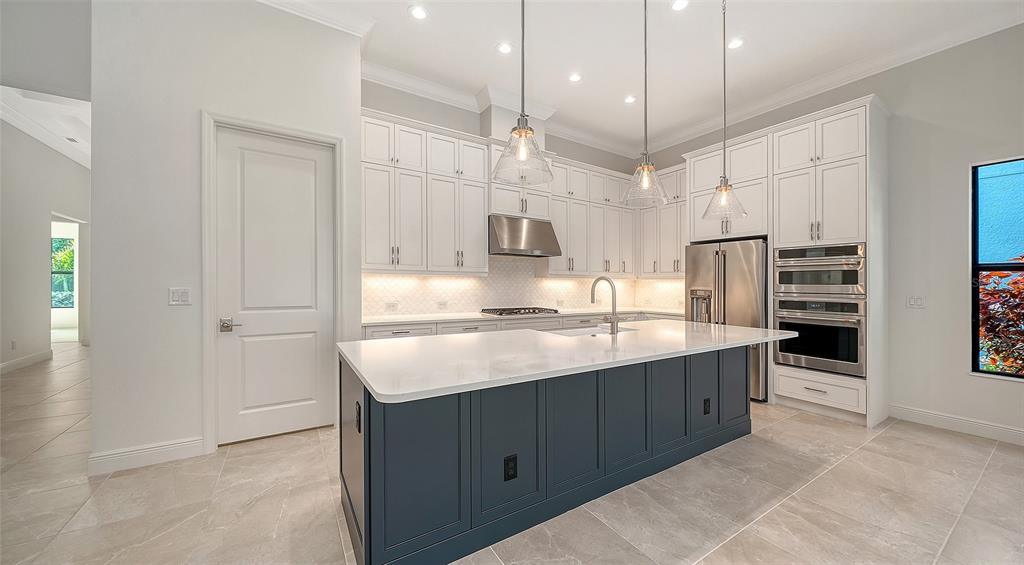 A modern kitchen features white cabinetry, a dark blue island, and stainless steel appliances — 524 BOCELLI DRIVE, NORTH VENICE, FL