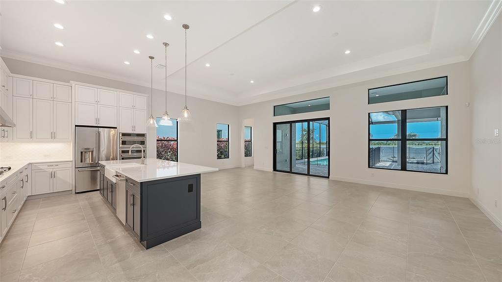 A modern kitchen with white cabinets and a dark blue island opens to a living area — 524 BOCELLI DRIVE, NORTH VENICE, FL