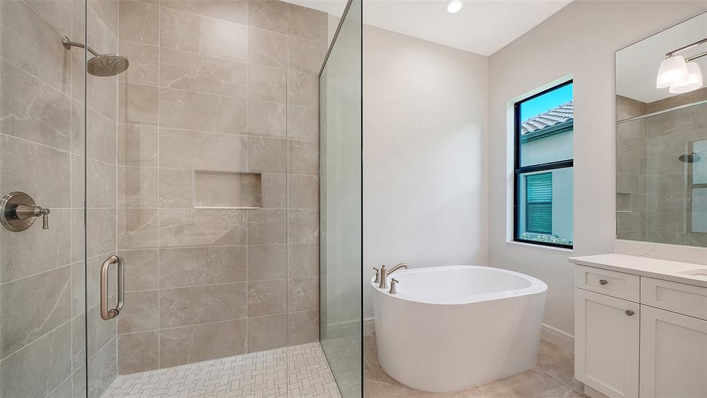 A modern bathroom features a glass-enclosed walk-in shower, a freestanding tub, and a white vanity — 524 BOCELLI DRIVE, NORTH VENICE, FL