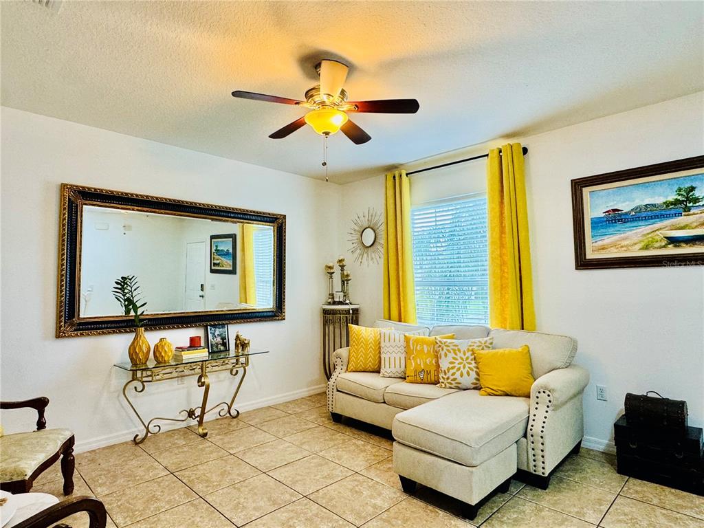 A living room features a sectional sofa, two accent chairs, a mirror, and tile flooring — 1868 MONTE CRISTO LANE, KISSIMMEE, FL