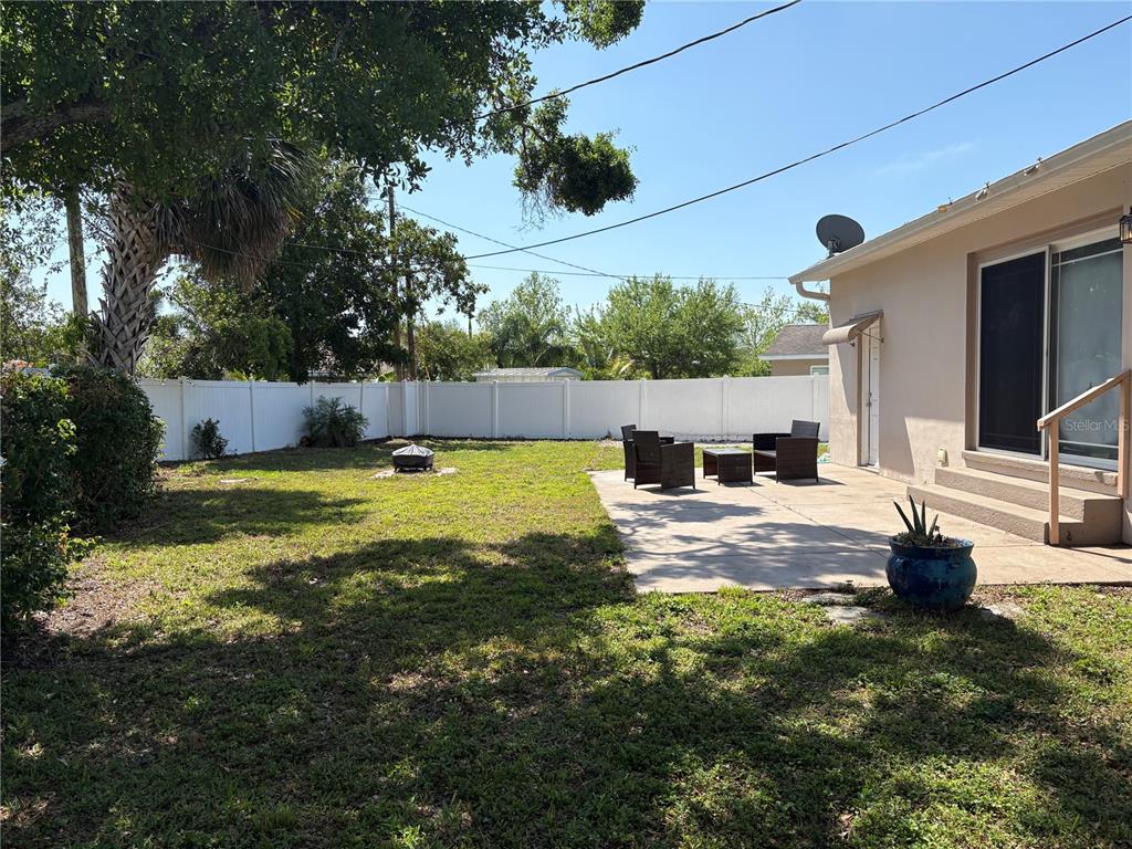 A backyard features a concrete patio with outdoor furniture, a fire pit, and a white fence — 6221 13TH AVENUE N, ST PETERSBURG, FL
