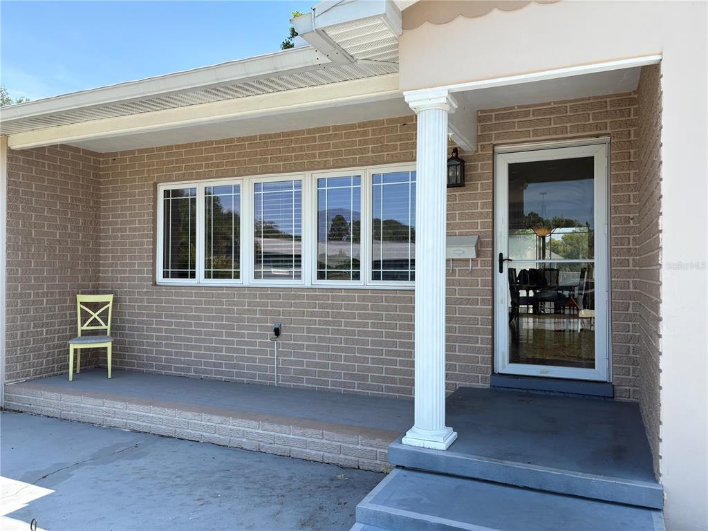 A brick house exterior features a covered front porch, a white column, and a glass door — 6221 13TH AVENUE N, ST PETERSBURG, FL