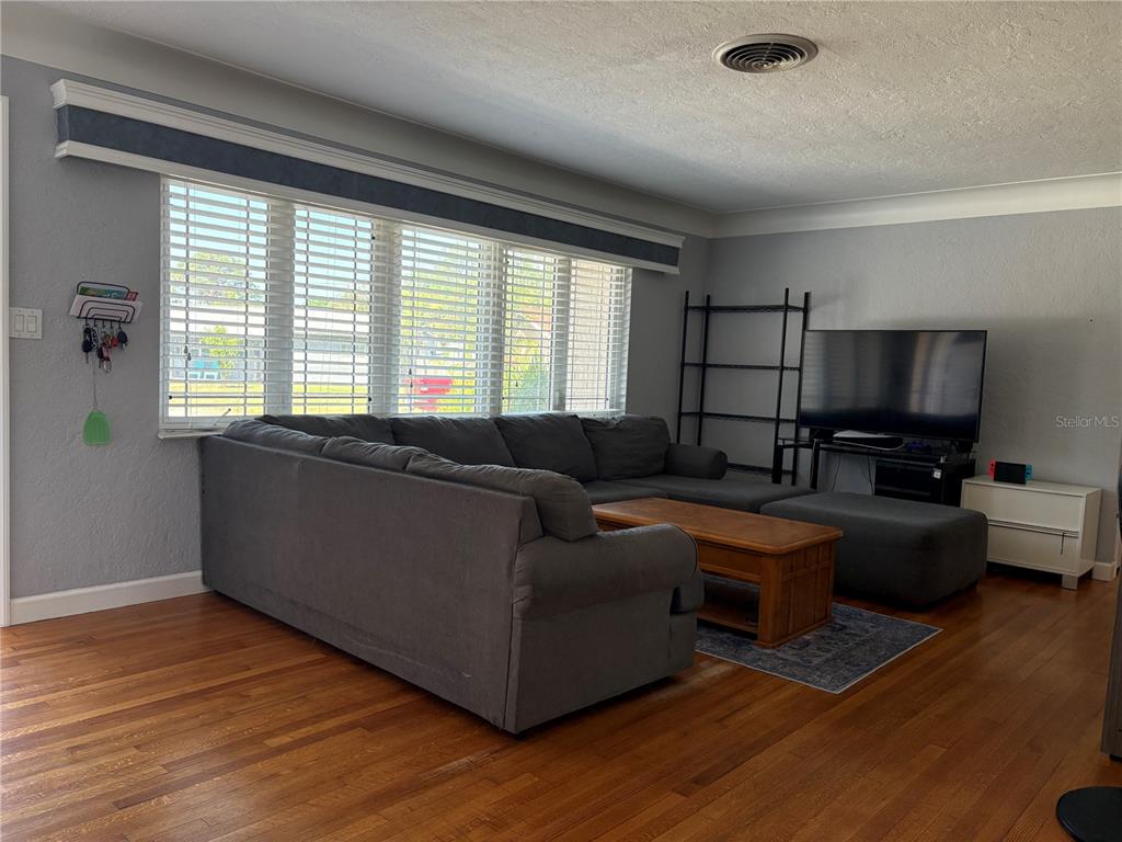 A living room features a large gray sectional sofa, a wooden coffee table, and hardwood floors — 6221 13TH AVENUE N, ST PETERSBURG, FL