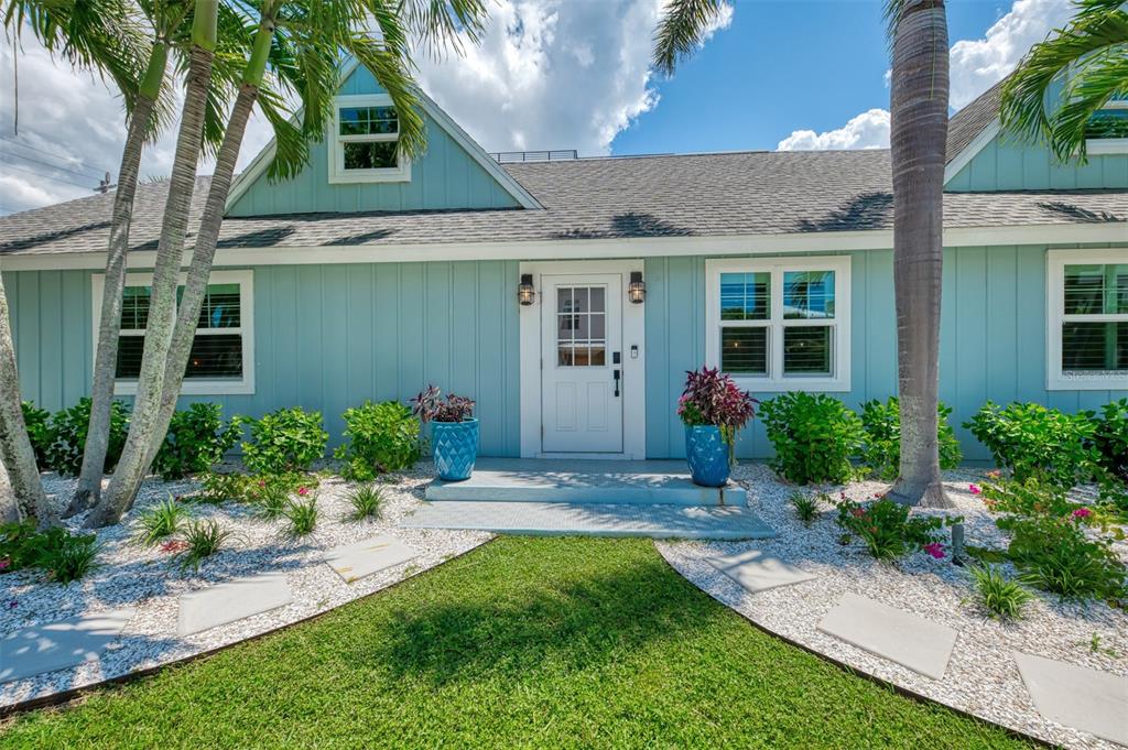 A light blue house with a white front door, palm trees, and a gravel garden — 1100 POINT OF ROCKS ROAD, SARASOTA, FL