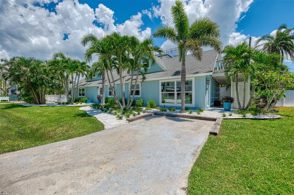 A light blue house with a concrete driveway, palm trees, and a landscaped front yard — 1100 POINT OF ROCKS ROAD, SARASOTA, FL
