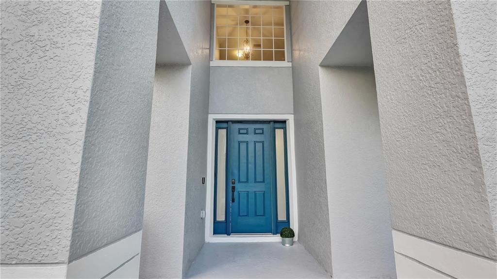 A blue front door is set within a recessed entryway beneath a tall window — 3833 SISKIN DRIVE, KISSIMMEE, FL