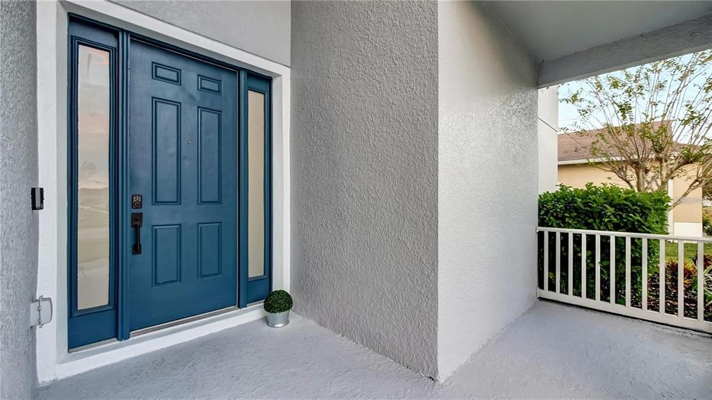 A blue front door with side lights sits on a covered porch with gray walls — 3833 SISKIN DRIVE, KISSIMMEE, FL