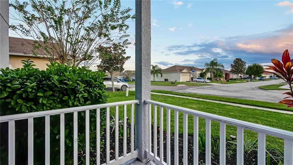 A view from a covered porch looking out over a suburban street and neighborhood homes — 3833 SISKIN DRIVE, KISSIMMEE, FL