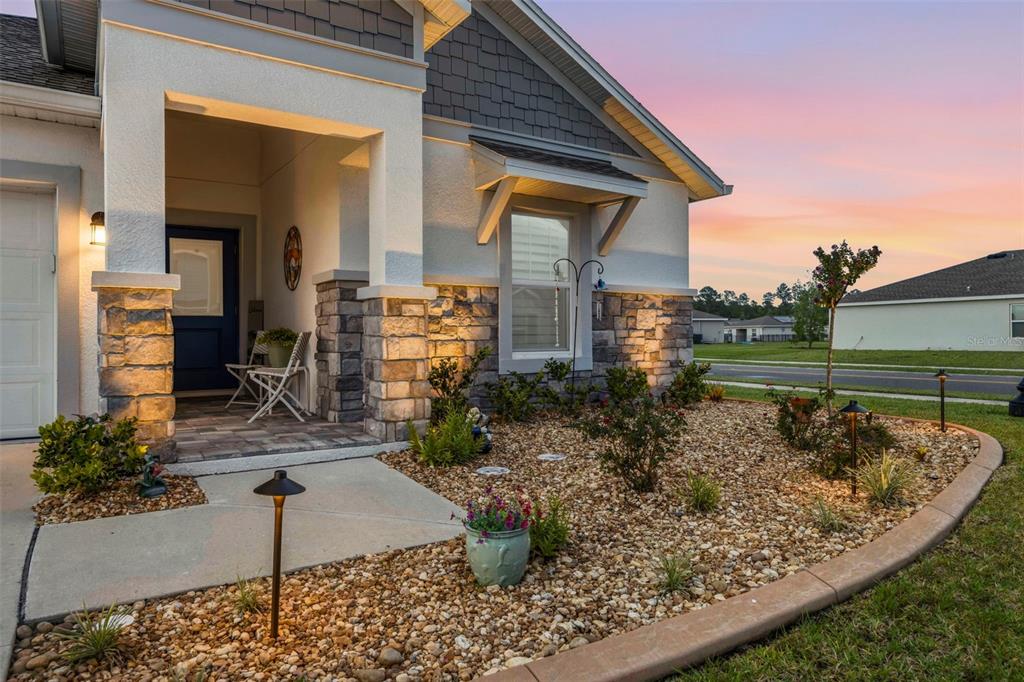 A front view of a house with a stone-accented porch, gravel landscaping, and exterior lighting — 1156 SAND TRAP COURT, DAYTONA BEACH, FL