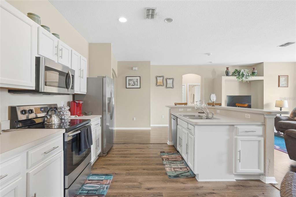 A kitchen with white cabinets, stainless steel appliances, and an island with a sink — 11436 LAGORCE AVENUE, SPRING HILL, FL