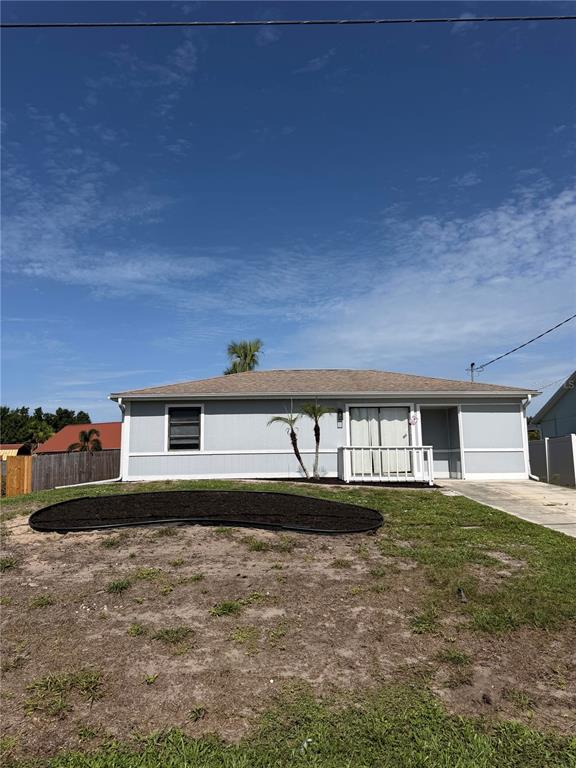 A single-story house with light gray siding, a shingled roof, and a front yard garden bed — 11748 OCEANSPRAY BOULEVARD, ENGLEWOOD, FL