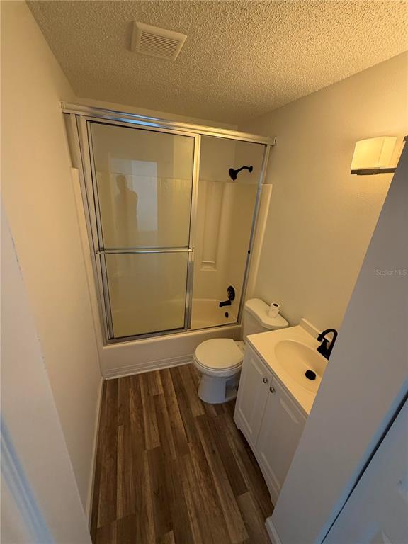 A bathroom features a shower-tub combo, a white vanity, and wood-look flooring — 11748 OCEANSPRAY BOULEVARD, ENGLEWOOD, FL