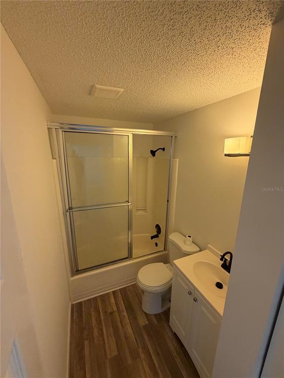 A small bathroom features a shower-tub combo, a white vanity, and wood-look flooring — 11748 OCEANSPRAY BOULEVARD, ENGLEWOOD, FL