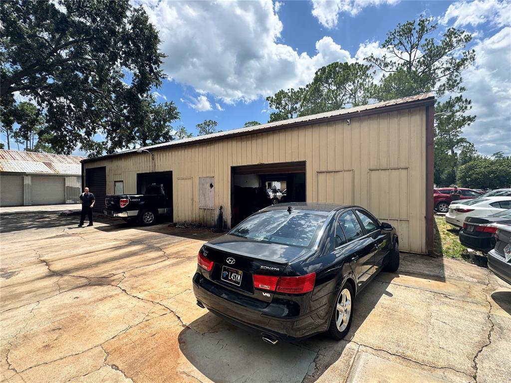 A black sedan is parked in front of a tan metal commercial garage building — 6 MARKET PLACE COURT, PALM COAST, FL