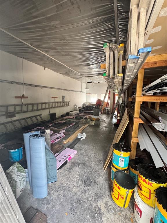 A cluttered storage room features concrete floors, exposed ceiling material, and various construction supplies — 6 MARKET PLACE COURT, PALM COAST, FL