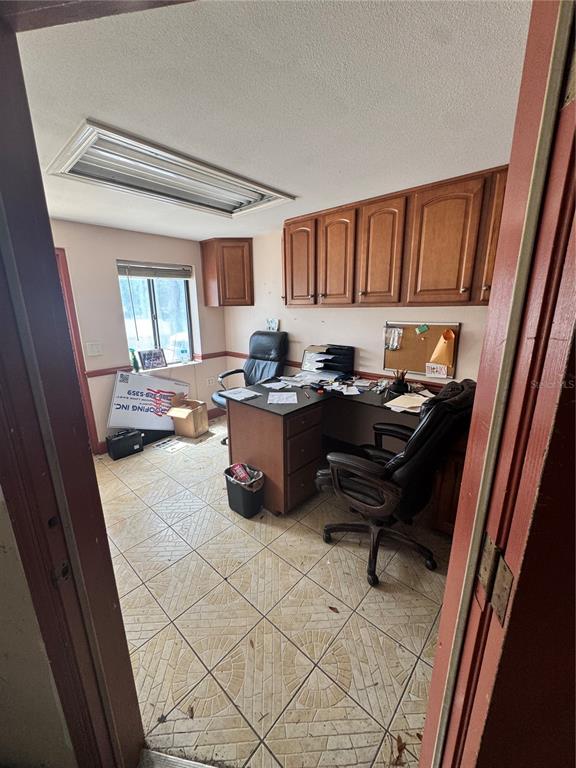 A home office features tile flooring, wood cabinets, a desk, and a window — 6 MARKET PLACE COURT, PALM COAST, FL