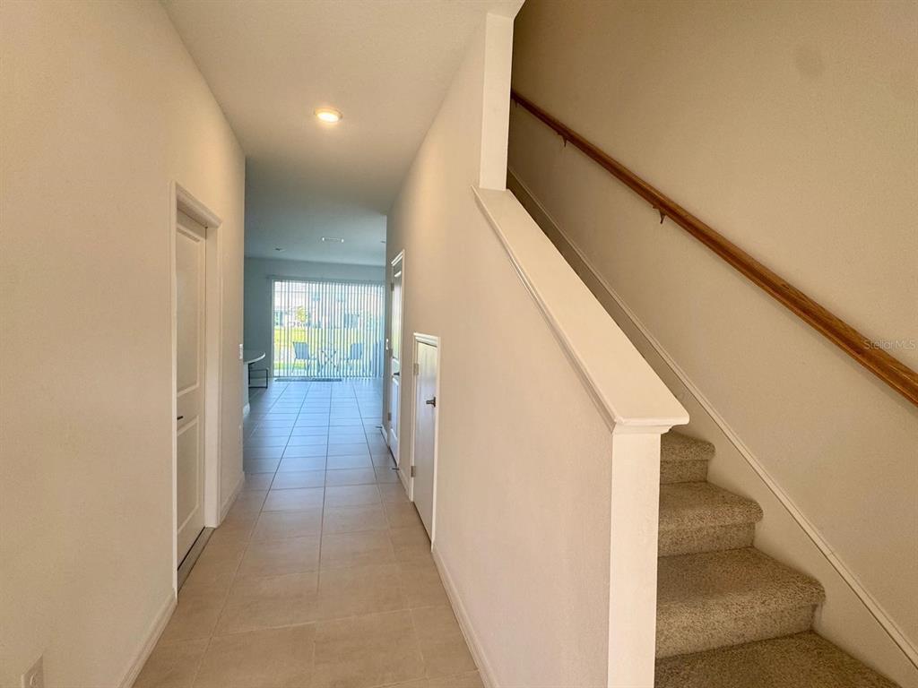 A hallway with tile flooring leads to a living area with stairs on the right — 5715 ARCHIPELAGO STREET, NOKOMIS, FL