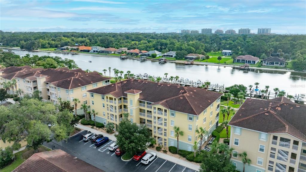An aerial view shows multi-story apartment buildings with brown roofs situated along a waterfront canal — 700 CANOPY WALK LANE UNIT 723, PALM COAST, FL