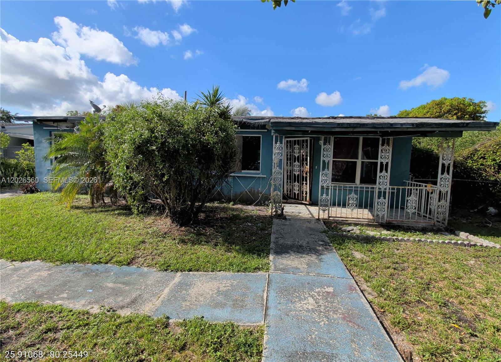 A single-story blue house features a front porch with decorative metal railings and security doors — 820 Curtiss Dr, Opa-Locka FL 33054, OPA-LOCKA, FL