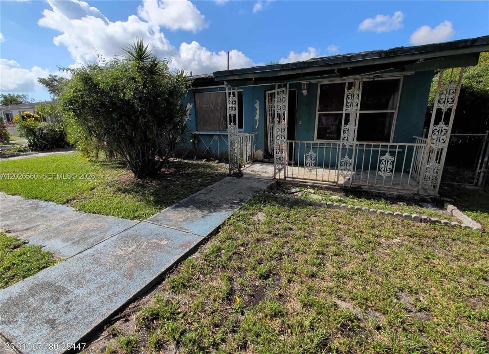 A single-story house with a blue exterior, a front porch, and a boarded-up window — 820 Curtiss Dr, Opa-Locka FL 33054, OPA-LOCKA, FL