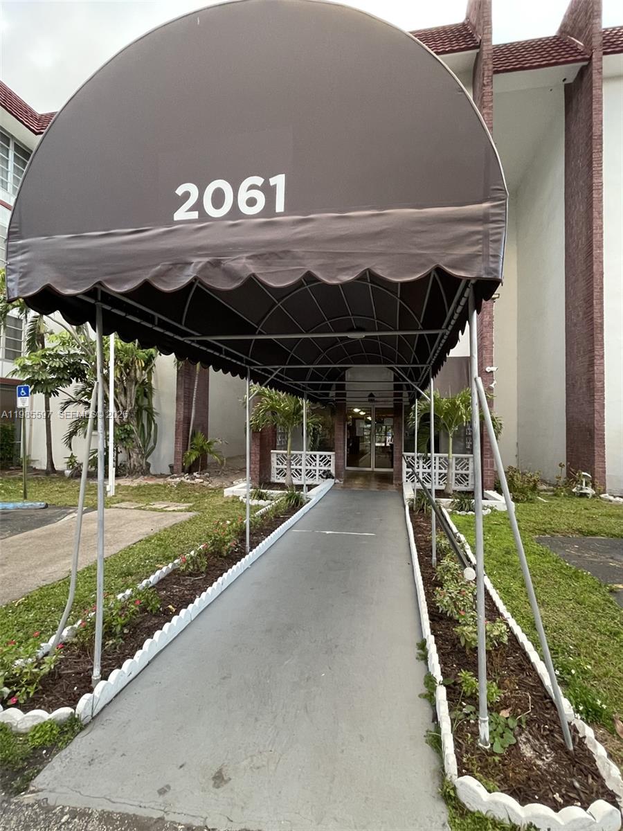 A multi-story apartment building features a brown entrance awning and a paved parking lot — 2061 NW 47th Ter # 306, Lauderhill FL 33313, LAUDERHILL, FL