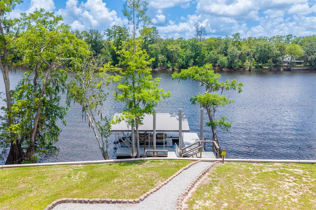 A gravel path leads to a covered boat dock on a calm river — 8213 RIVERVIEW ROAD, FANNING SPRINGS, FL