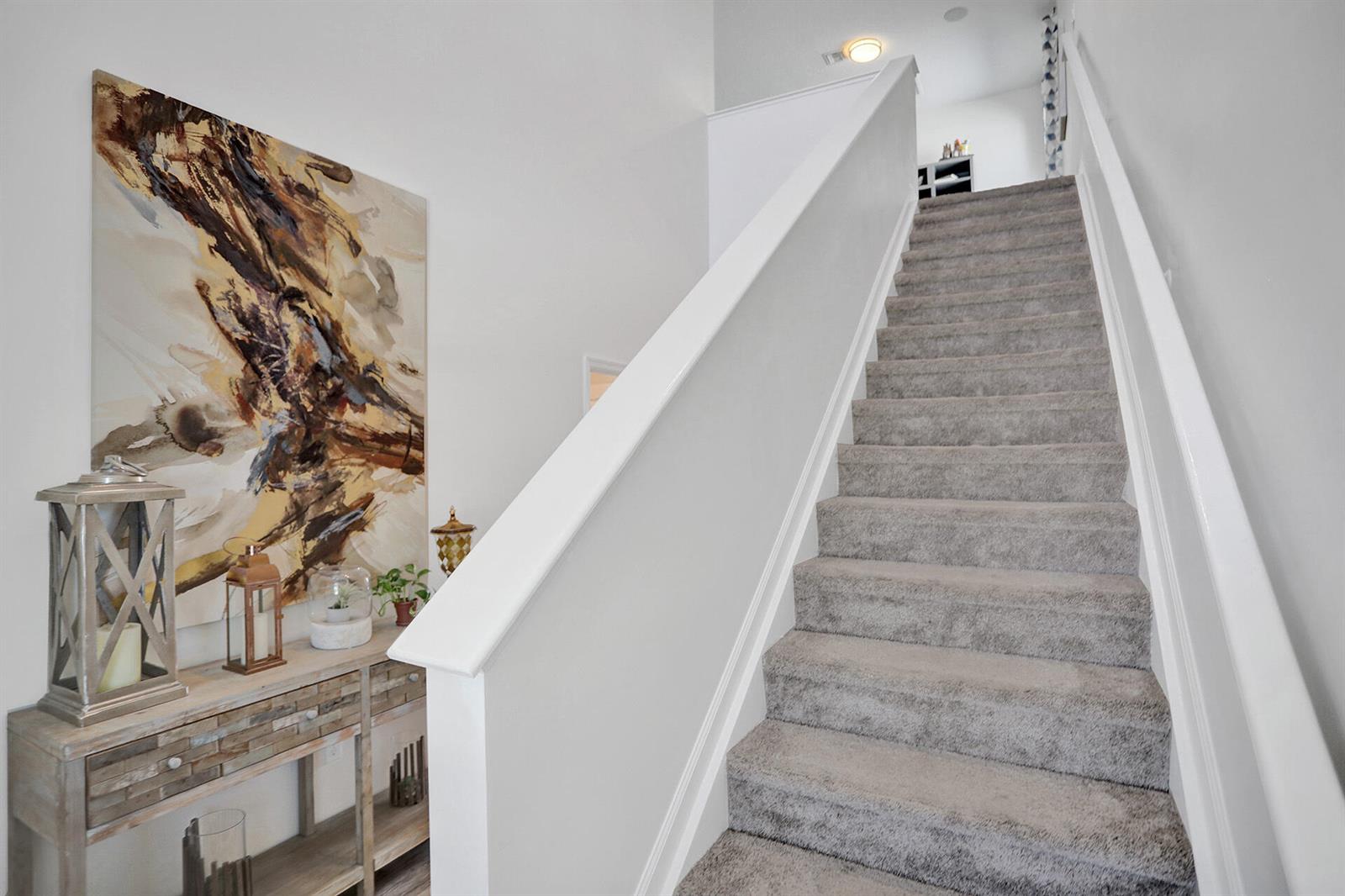 A carpeted staircase with a white railing leads upward next to a wooden console table — 1905 Vernon Street, FL 33460, FL