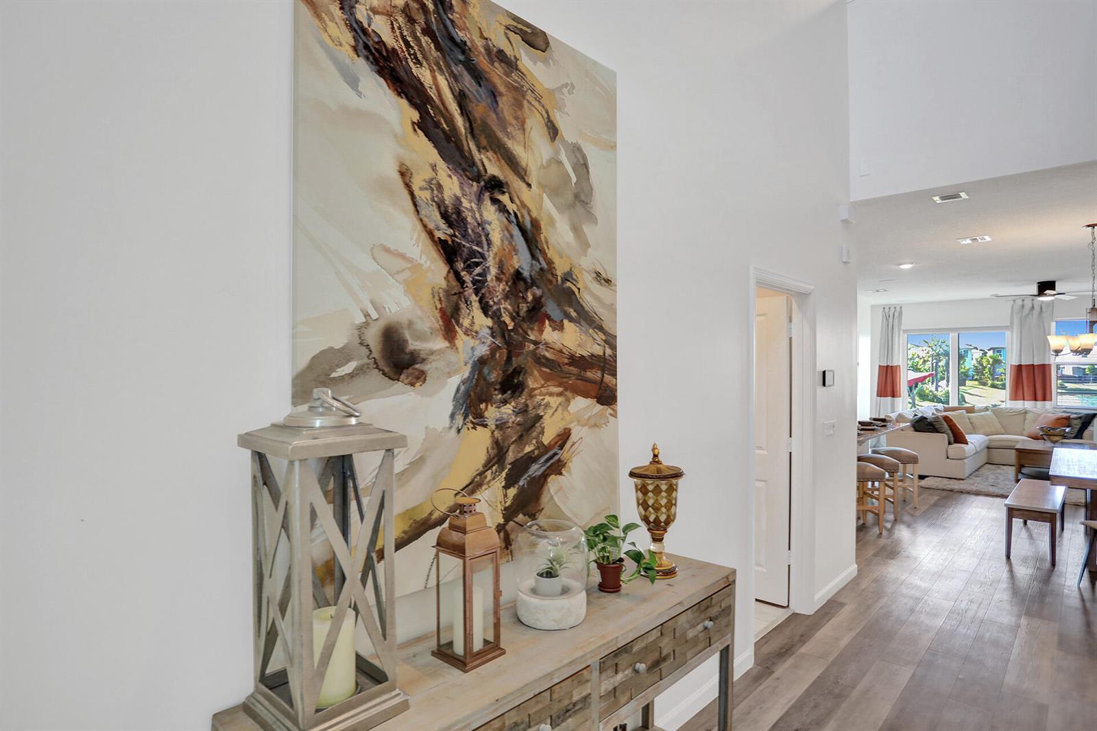A hallway features a large abstract painting above a wooden console table with decor — 1905 Vernon Street, FL 33460, FL