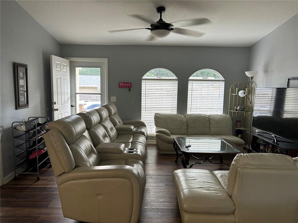 A living room features light-colored leather seating, a glass-top coffee table, and arched windows — 10013 OSLIN STREET, TAMPA, FL