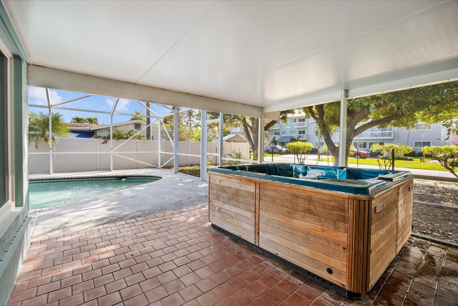 A covered patio features a wooden hot tub, brick flooring, and an adjacent swimming pool — 800 SE 13th Court, Deerfield Beach FL 33441, DEERFIELD BEACH, FL