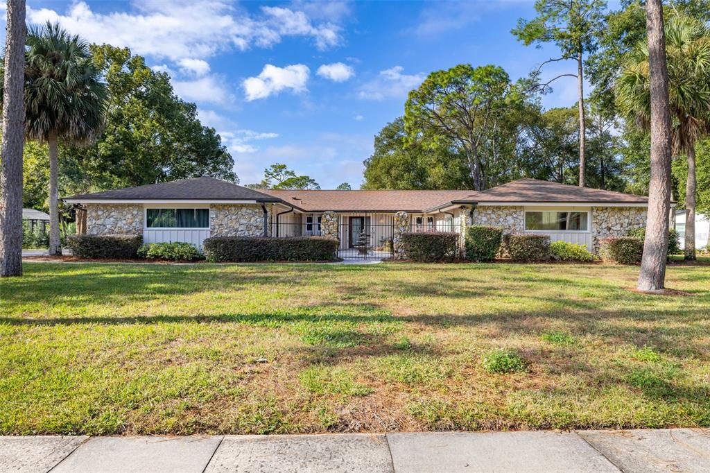 A single-story house with a stone facade and a central gated courtyard entrance — 204 BLUE LAKE DRIVE, LONGWOOD, FL