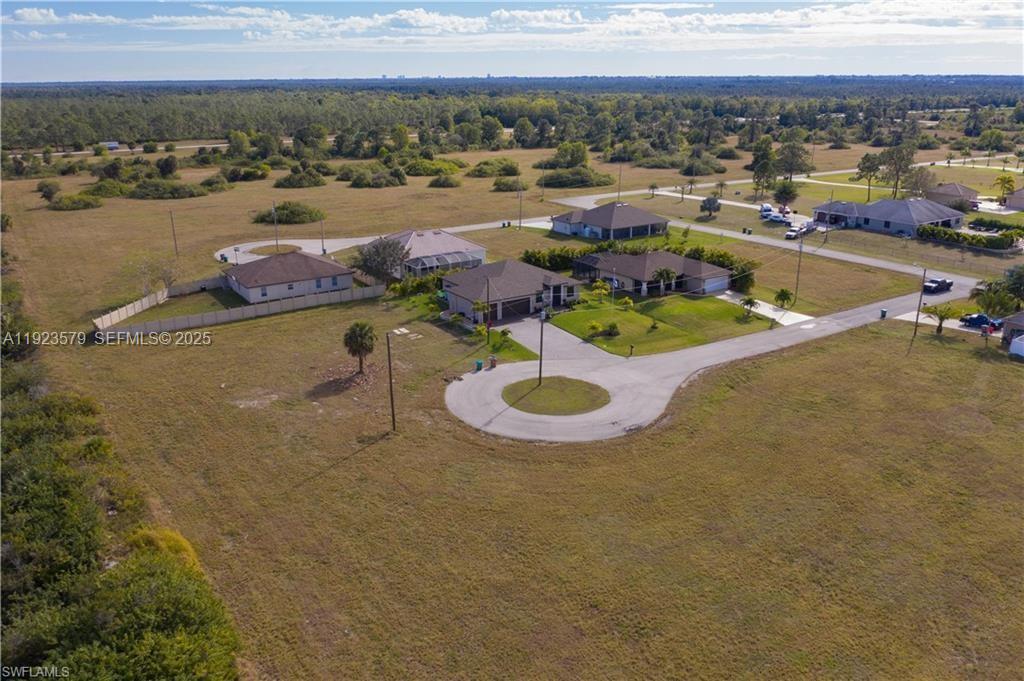An aerial view shows several suburban houses situated on a large, grassy lot — 3923 NW 33RD PL, Cape Coral FL 33993, CAPE CORAL, FL