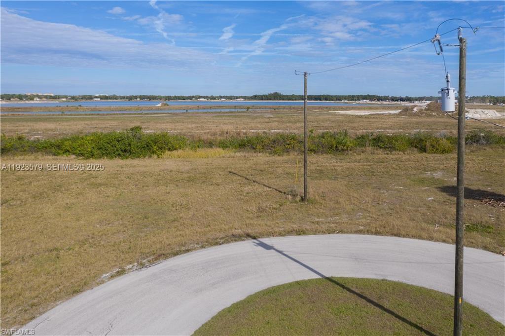 An aerial view shows a vacant lot with a curved road and utility poles — 3923 NW 33RD PL, Cape Coral FL 33993, CAPE CORAL, FL